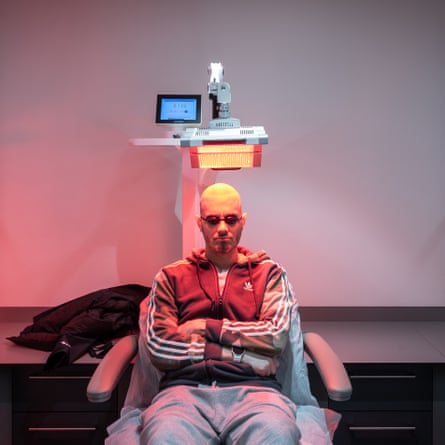 A man sits below a red LED light
