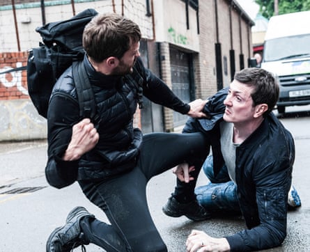 A man pulls his fist back to punch another man on the pavement