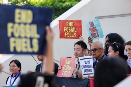 Activists hold signs that read ‘end fossil fuels’.
