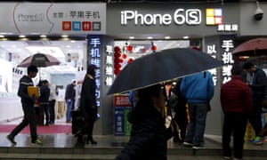 people walk past an iPhone shop in China