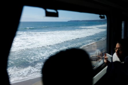 Train passengers look out at the ocean.