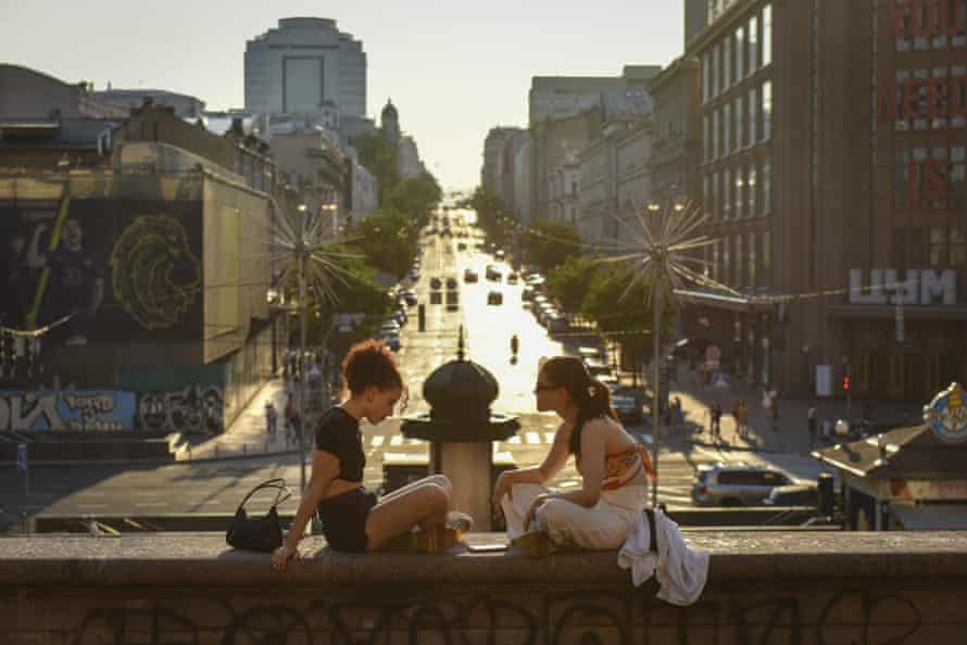 Two young women sit on a wall at sunset in downtown Kyiv, Ukraine, 5 July.