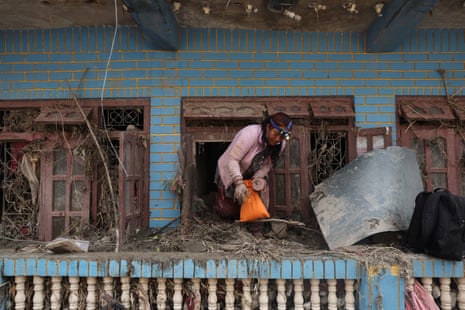 A woman climbs out of a window after looking for belongings in a mud-filled house at Devighat, Nepal.