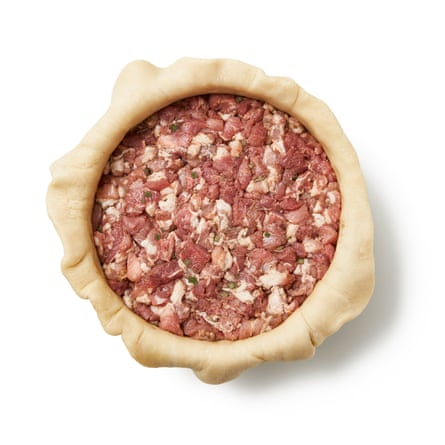 Versez la garniture de porc dans la pâte - elle rétrécira pendant la cuisson, alors tassez-la fermement. Replier la pâte qui dépasse sur la viande sur les bords. Étalez le reste de pâte, découpez un cercle un peu plus grand que la circonférence du moule, puis placez-le sur la garniture.