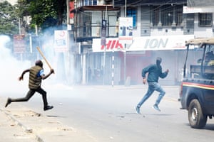 A pro-government counter-protester holds a wooden club as he runs during a protest over the death of Kenyan blogger Albert Ojwang in police custody, in downtown Nairobi