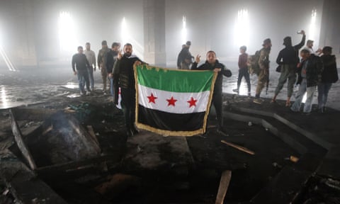 Rebel fighters stand next to the burned gravesite of Syria’s late president Hafez al-Assad at his mausoleum in the family’s ancestral village of Qardaha.