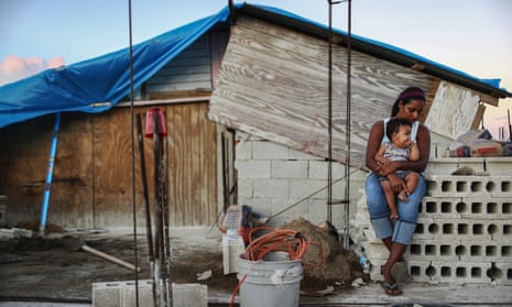 A mother holds her nine-month-old baby at their makeshift home, under reconstruction after being mostly destroyed by Hurricane Maria, in San Isidro, Puerto Rico, on 23 December 2017. 