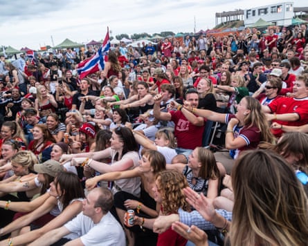 A crowd of people sitting in a field perform the Viking row