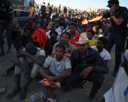 Migrants wait in line to receive food and beverage from the Red Cross, following mass crossings of migrants on foot and by sea from Morocco into Spanish territory, in Ceuta, Spain.