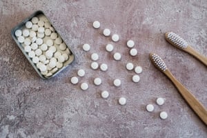 Toothpaste tablets next to wooden toothbrushes.