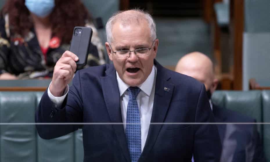 Scott Morrison waves around his mobile phone during question time in 2021. Morrison’s office has been ordered to search through his phone for messages from his friend and prominent Qanon conspiracy theorist Tim Stewart.