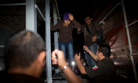 Immigration officials remove Central American migrants from a northbound freight train during an after-midnight raid by federal police in San Ramon, Mexico, last year.
