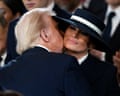 A man kisses a woman wearing a hat