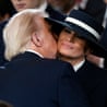 A man kisses a woman wearing a hat