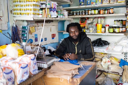 Ridley Road market shop worker Jacob Addo sits surrounded by various products