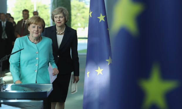 German Chancellor Angela Merkel and British Prime Minister Theresa May walk past European Union flags in Berlin, Germany. 