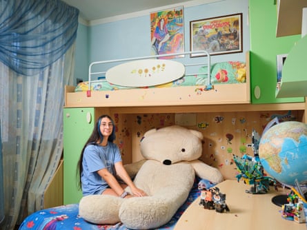 Sofia sitting on a bunk bed in her room with a huge teddy bear