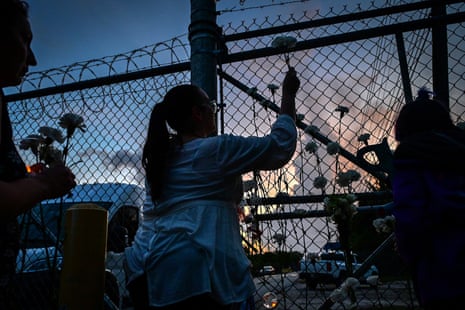 People place white carnation flowers on the fence of the Krome detention center during a vigil protesting Ice and mass deportations in Miami on 24 May.