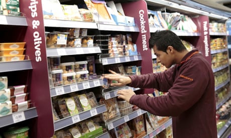 An employee stocks a shelf at a Sainsbury's Local store in central London