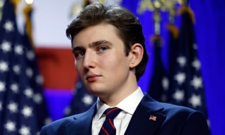 Barron Trump standing in front of American flags
