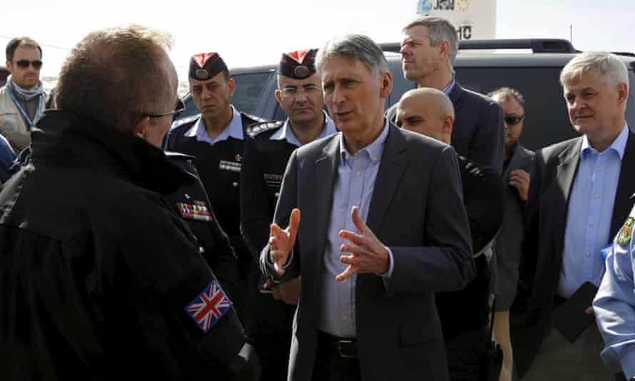 Philip Hammond speaks with former British police officers at a refugee camp in Jordan.