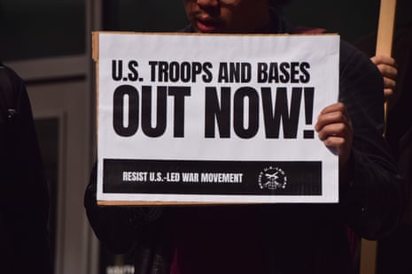 A protester holds a placard opposed to US troops and military bases during a demonstration outside the Embassy of USA London, England, United Kingdom - 22 Mar 2026