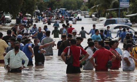 Residents wade through a flooded road in the aftermath of Hurricane Eta in Planeta, Honduras.