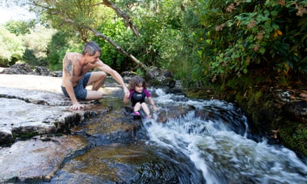 A man holds a child who is sitting in the river