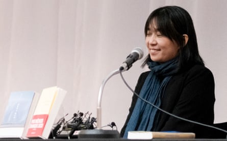 Han Kang smiles as she speaks into a microphone on stage.