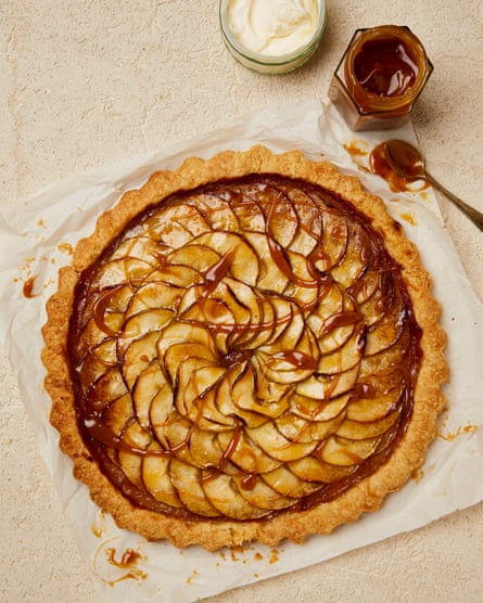 Overhead shot of a round tart decorated with thin slices of apple and drizzled with dark caramel