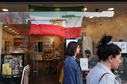 People queue in a shop in Finchley displaying the Iranian flag