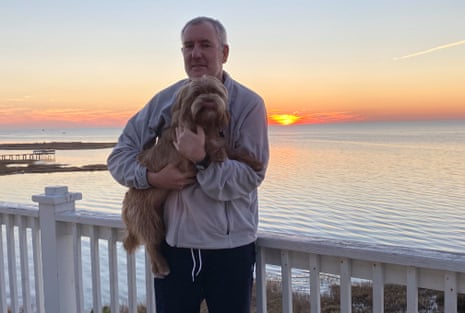 David holding his dog photographed against a sunset