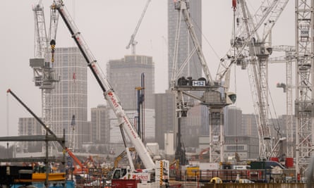 A huge construction site full of large cranes, with newly built high-rise blocks of flats in the background