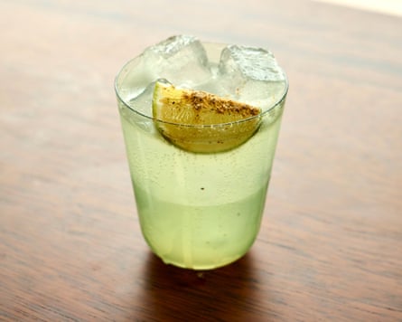 A green coloured drink filled with ice and topped with a slice of lime.