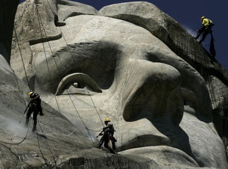 Park workers scale the face of Thomas Jefferson’s face carved into a mountain