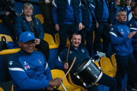 Colombian soldier David sits in the stand with a drumstick next to another fan with a drum