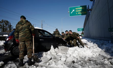 Greek soldiers remove snow in front of cars on Attiki Odos.
