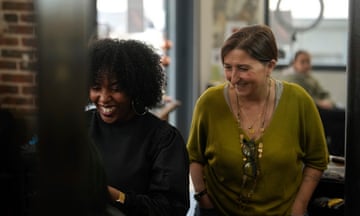 Hairdresser, Aude Livoreil-Djampou, right, laughs with one of the staff in her hairdressing salon, in Paris. French lawmakers are passed a bill that would ban discrimination over the texture, length, color or style of someone's hair.