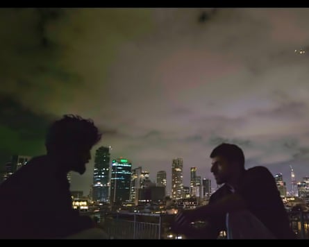 Two men’s silhouettes seen in profile against a hazy night sky and city skyline