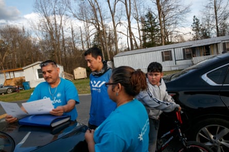 people wearing blue shirts look at paper as child stands behind them