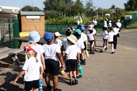 A group of children in PE kit and sun hats