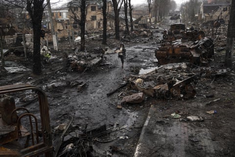 A woman walks past destroyed Russian tanks in Bucha, in the outskirts of Kyiv,