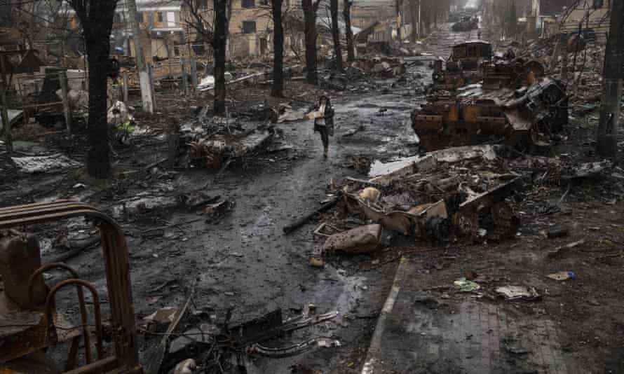 A woman walks amid destroyed Russian tanks in Bucha, on the outskirts of Kyiv, Ukraine, on Sunday