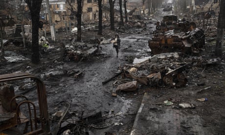 A woman walks past destroyed Russian tanks in Bucha, in the outskirts of Kyiv,