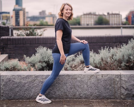 Jess Murray in running gear stretching one leg on a knee-high garden landscaping edge