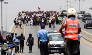 Police in Luanda watch a protest against the rising cost of living and corruption in Angola, one of the oil-producing states the report warns are vulnerable.