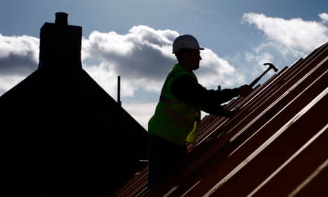 A builder works on the roof beams of a residential property for Persimmon .