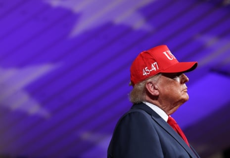 Man in suit and red Maga hat looks to side