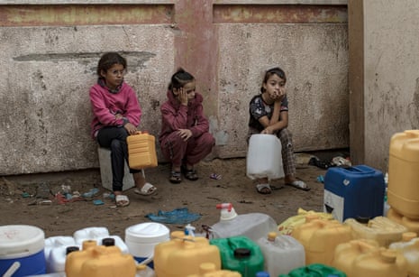 Palestinian children wait inside Nasser hospital in Khan Yunis to fill containers with water, in the southern Gaza Strip, 14 November 2023.