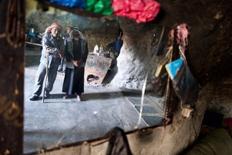 Two older men seen in a mirror hanging in a cave